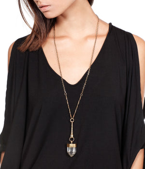 Long necklace with a pendant worn by a person against a white background