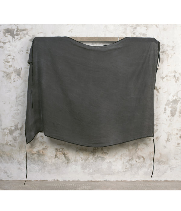Dark gray linen shawl draped over a wooden frame against a textured white wall.