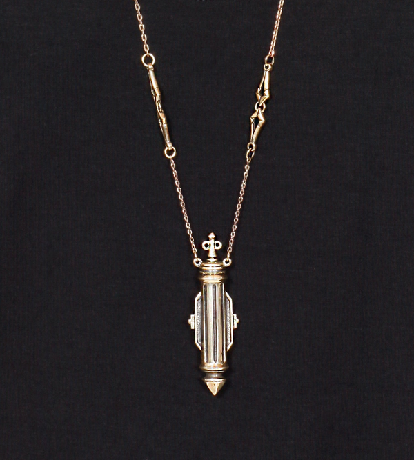 Gold necklace with a decorative pendant on a black background