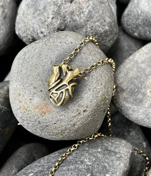 Bronze necklace with a heart pendant on a stone surface